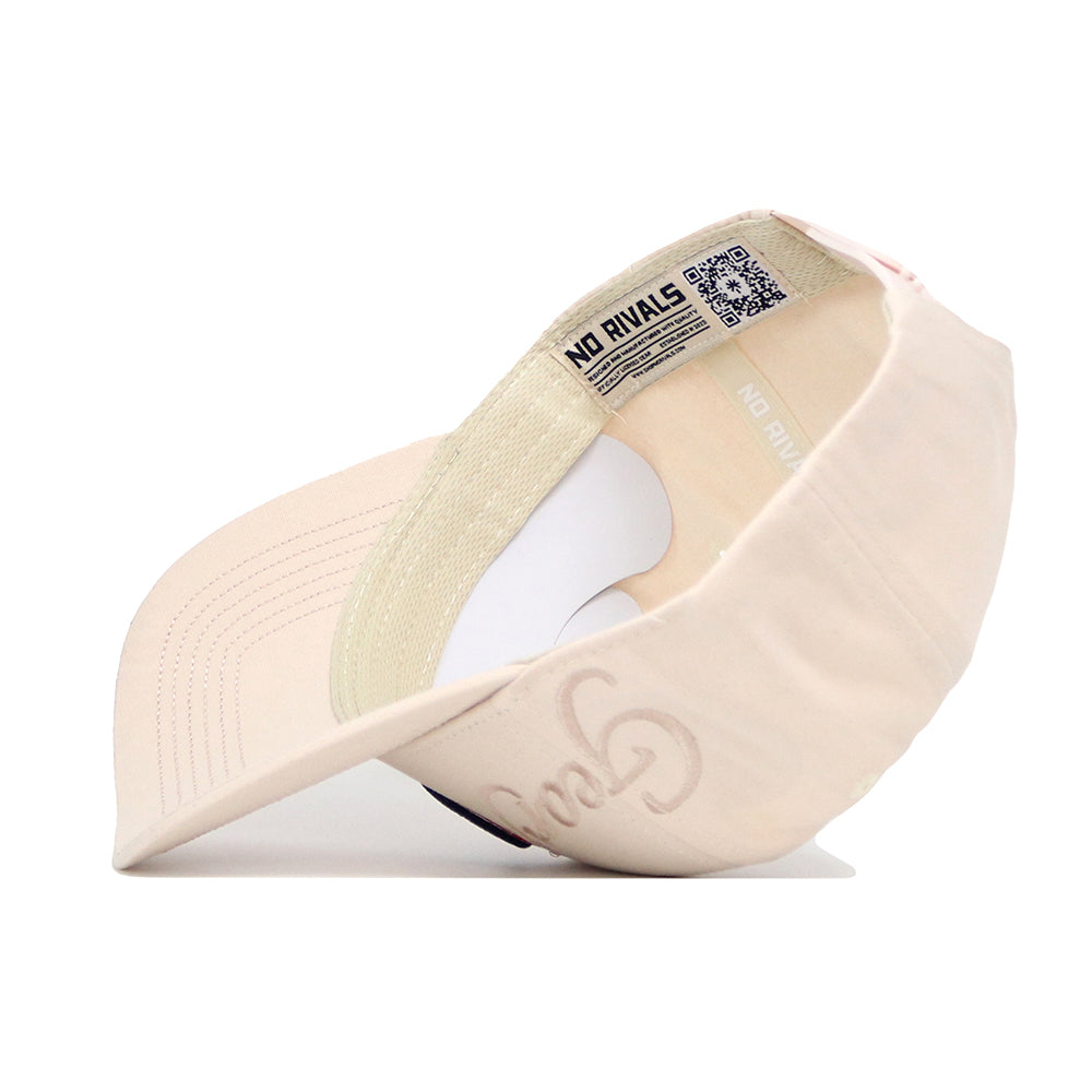 The Georgia Stacked Hat by No Rivals is a beige structured cap made from high quality cotton, featuring “Good” embroidered on the front and an interior label that reads “NO RIVALS.” The image shows it flipped to reveal the underside of the brim.