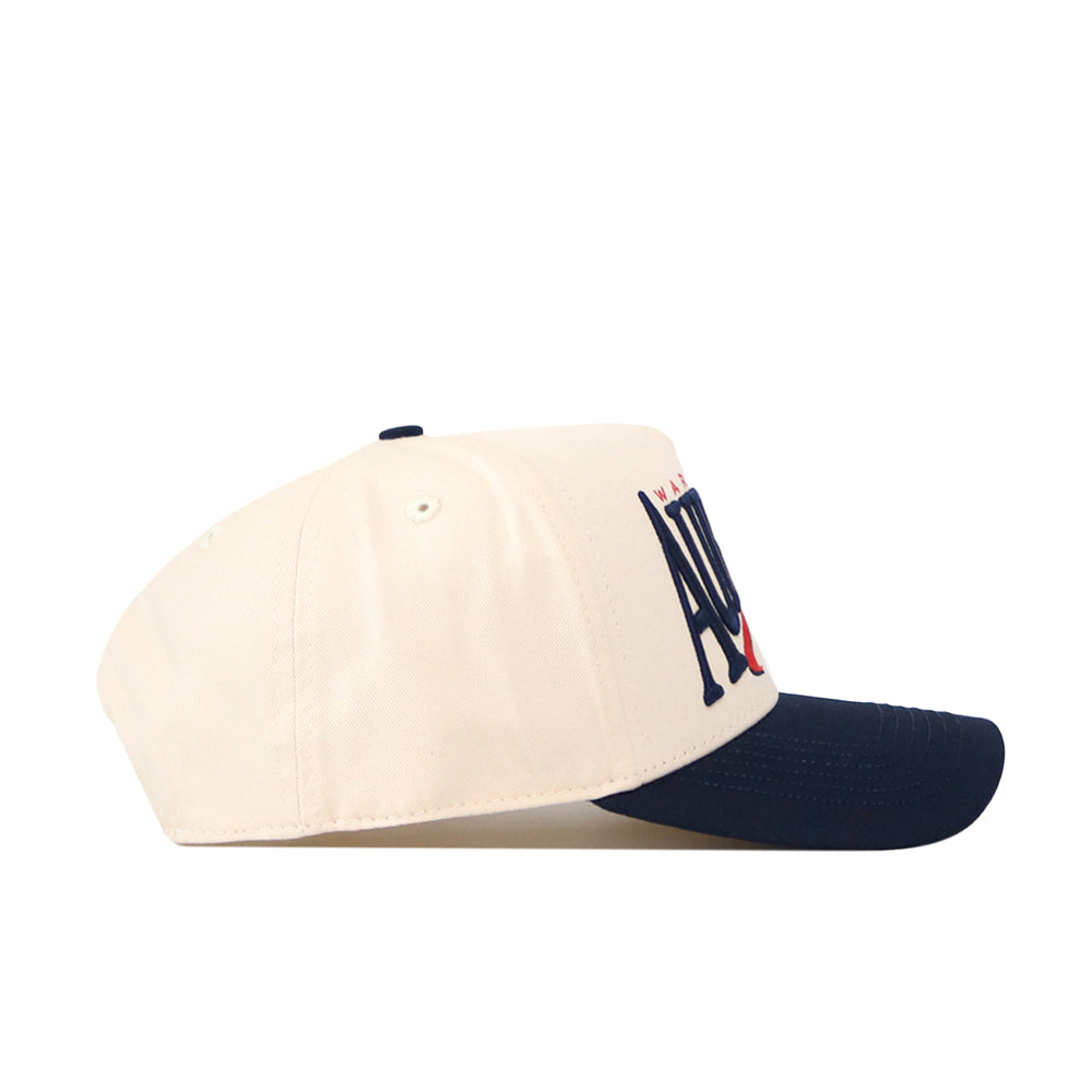 A side view of the No Rivals Auburn Tigers Stride Hat, featuring a cream-colored crown, dark blue brim, and officially licensed embroidered Auburn letters on the front.