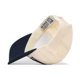 A cream and navy blue Auburn Tigers Stride Hat by No Rivals is shown from the bottom, highlighting the inside labels and stitching of this officially licensed snapback.