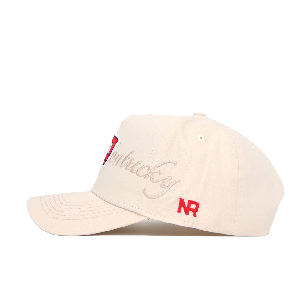 The Western Kentucky Stacked Hat by No Rivals is a beige cotton snapback with a structured fit, slightly curved brim, vent holes, "Kentucky" embroidered in cursive on the side, and red NR initials near the back.