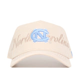 The No Rivals North Carolina Stacked Hat is a beige cotton baseball cap featuring "North Carolina" in script and a bold blue UNC logo above the brim. It has an adjustable snapback and is officially licensed.