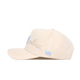 The North Carolina Stacked Hat by No Rivals is a beige cotton cap with blue embroidered text and NR on the side. It features a curved brim, ventilation eyelets, and an adjustable snap back for the ideal fit.