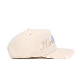 The No Rivals North Carolina Stacked Hat is a beige baseball cap with light brown and blue embroidery on the front, made from premium cotton. It features ventilation eyelets, a curved brim, and a classic snapback closure.