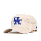The No Rivals Kentucky Stacked Hat is a beige snapback made from high-quality cotton, featuring a large blue UK logo on the front, "Wildcats" embroidered on the back, and an official small blue logo on the side.