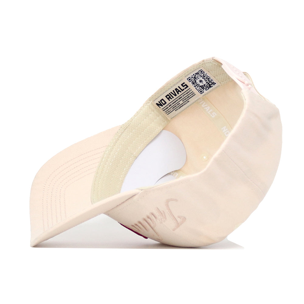 A light beige Indiana Stacked Hat by No Rivals, shown upside down, reveals its inner labels, stitching, and a QR code on the band with "NO RIVALS." The front displays subtle embroidered text.