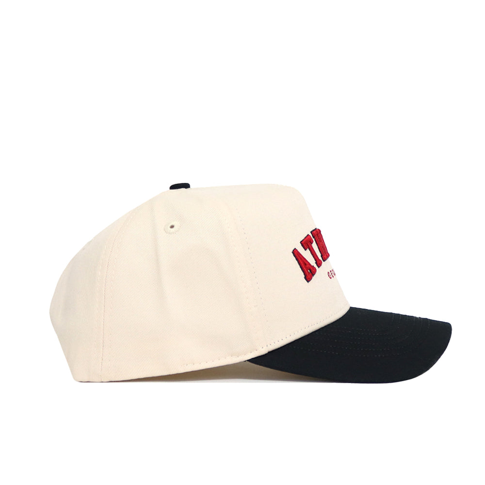 The No Rivals Athens Hometown Hat is a beige snapback with a black brim, red embroidered front text, and structured fit. Made from high-quality cotton, it's shown in a side view.
