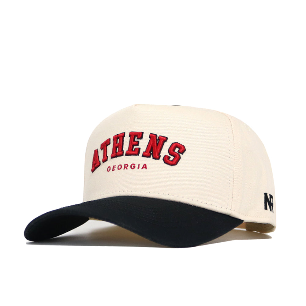 The Athens Hometown Hat by No Rivals is a cream snapback with a black brim, made from high quality cotton. It has "ATHENS" in large red letters, "GEORGIA" below, a small black logo on the side, and a structured fit.