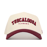 The No Rivals Tuscaloosa Hometown Hat features beige cotton fabric, "Tuscaloosa" in large red and "Alabama" in smaller red embroidery, a maroon curved brim, and a structured fit for comfort.