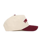 The No Rivals Tuscaloosa Hometown Hat is a cream snapback with a maroon brim and red embroidered text on the front, made of cotton, shown in side profile against a white background.