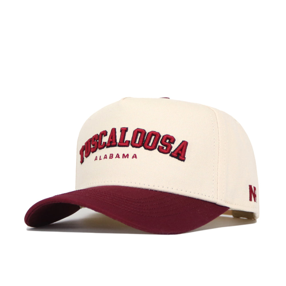 The No Rivals Tuscaloosa Hometown Hat features a cream cotton snapback, maroon brim, “Tuscaloosa Alabama” embroidered in red and black, a small N logo on the side, and a structured fit for lasting comfort and style.