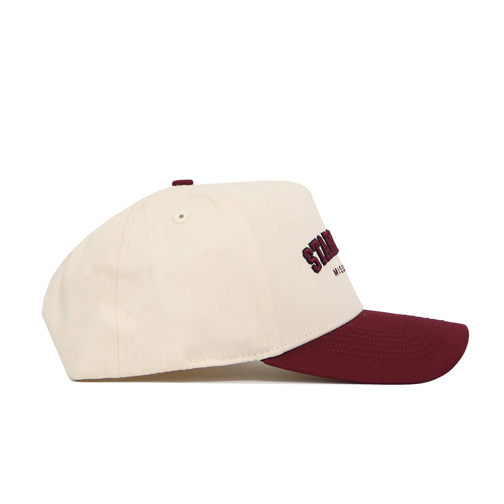 The Starkville Hometown Hat by No Rivals is a cream snapback with a maroon brim and maroon embroidered front text, made from high-quality cotton and shown in side profile.