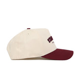 The Starkville Hometown Hat by No Rivals is a cream snapback with a maroon brim and maroon embroidered front text, made from high-quality cotton and shown in side profile.