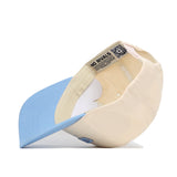 The Chapel Hill Hometown Hat by No Rivals, shown in beige and light blue turned on its side, reveals an inside label with the brand name and a QR code on the inner band, highlighting its structured snapback fit.