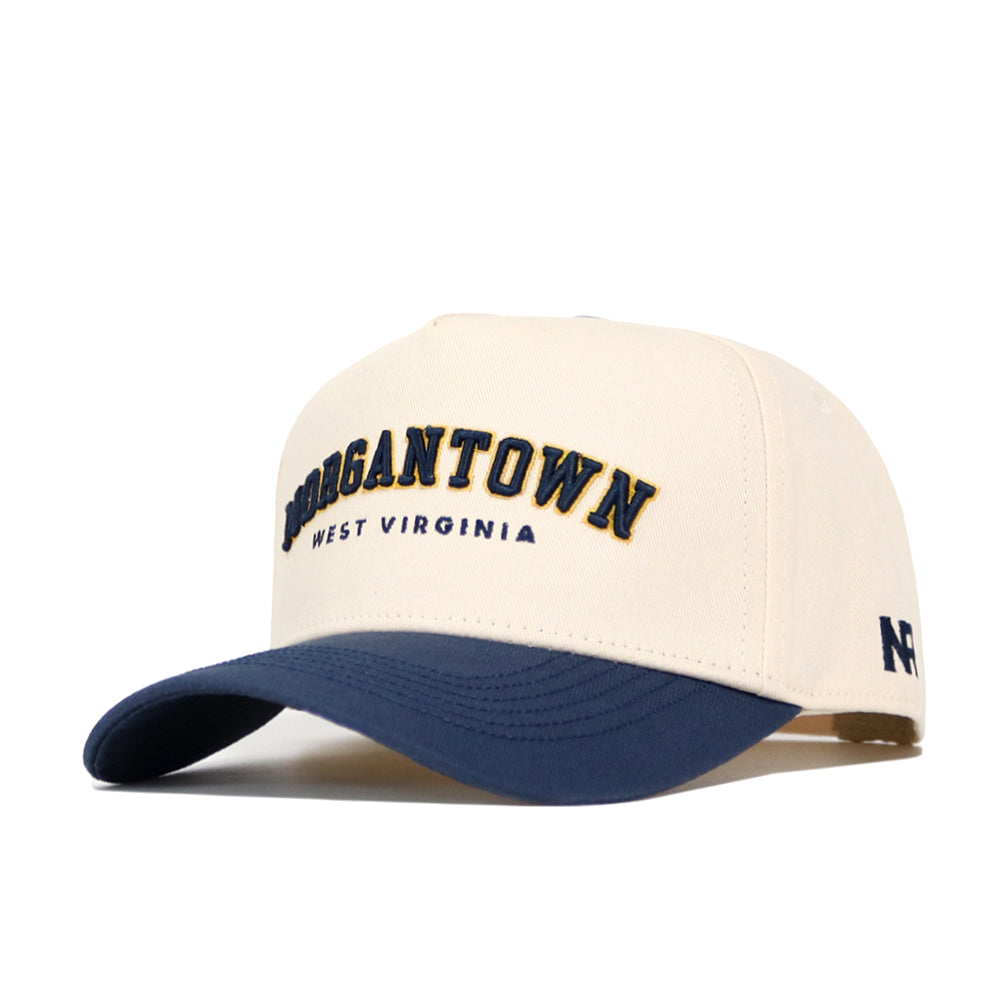 The No Rivals Morgan Town Hometown Hat is a cream snapback with a navy brim, made from premium cotton. "MORGANTOWN" in large navy and gold and "WEST VIRGINIA" in small navy accent the structured, classic look.