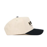 Side view of the No Rivals Boone Hometown Hat, a cream baseball cap with black brim. Made from quality cotton, it has black and gold embroidery on the front, a structured fit, snapback closure, and is shown on a white background.