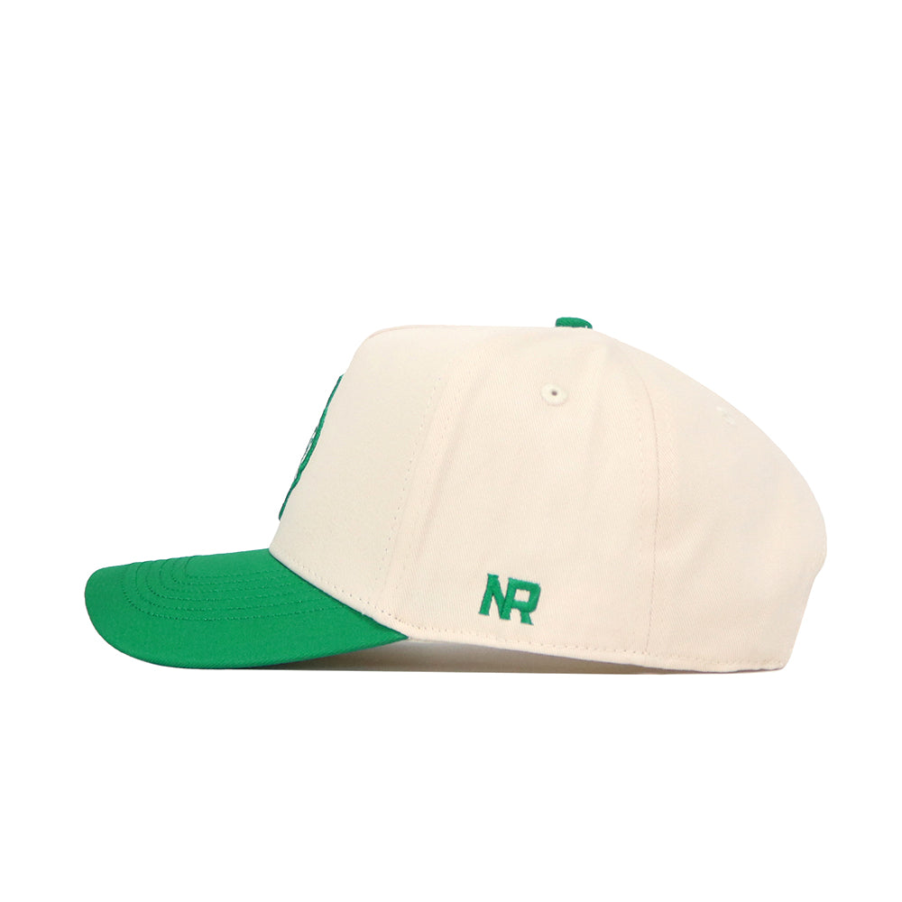 The No Rivals North Texas Logo Patch Hat is a cream snapback made from quality cotton, with a green brim and green NR initials embroidered on the side, shown in side profile against a white background.