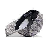 The Montana State Outland Hat by No Rivals is shown upside down, displaying its camouflage pattern, a black inner band with the NO RIVALS logo, and a white paper insert inside the crown.