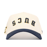 The No Rivals Upside Down BUCS Hat - ETSU - Classic Colors is a structured white snapback with a dark blue brim, made from high-quality cotton. "BUCS" is embroidered upside down in bold blue and yellow on the front.
