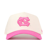 The No Rivals North Carolina Pink Out Hat is a white baseball cap with a pink brim, featuring a large pink interlocking NC logo embroidered on the front. This officially licensed snapback combines comfort and style while supporting an important cause.