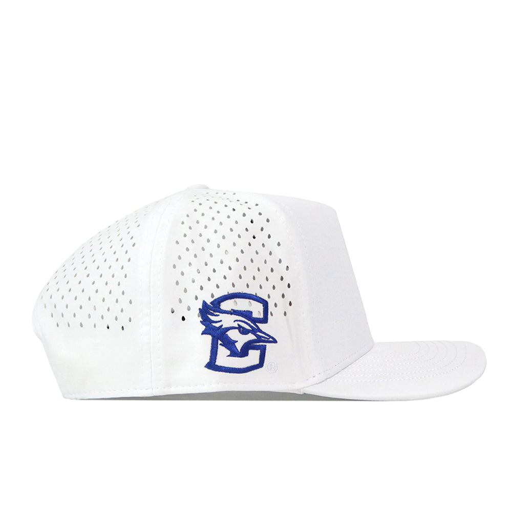 The Creighton Bluejays Volleyball Hat - White by No Rivals is a white perforated baseball cap made from performance fabric, featuring a blue bird and letter C embroidered logo on the side panel. This hat has a flat brim, structured design, and an adjustable snap back closure for a perfect fit.