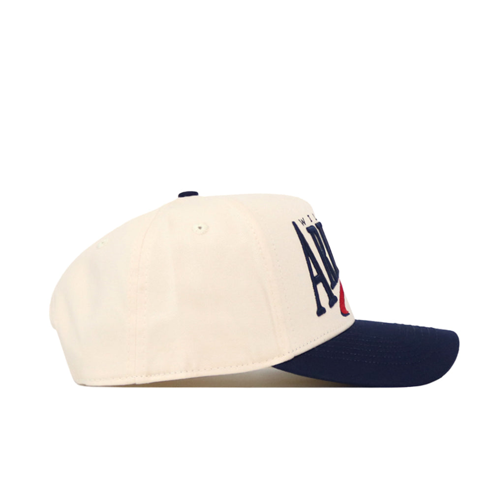 The Arizona Wildcats Stride Hat by No Rivals is a white baseball cap with a navy blue brim, displayed in a side view. Made from high quality cotton, this hat offers a structured fit for lasting comfort. The front showcases large dark blue text with a small red accent, while the top is completed with a navy button and matching ventilation holes. This classic snapback combines style and durability, making it perfect for everyday wear.
