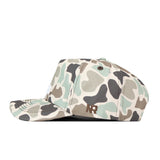 A side view of the No Rivals Ole Miss Rebels Huntsman Hat, a flat-brim snapback crafted from high-quality cotton, showcases a green, beige, and brown camouflage pattern with “NR” embroidered in brown on the side for both comfort and durability.
