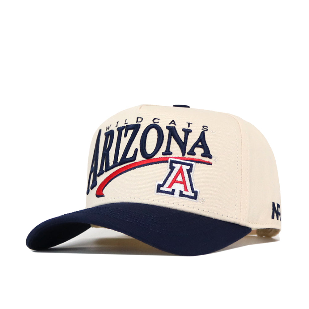 Introducing the Arizona Wildcats Stride Hat by No Rivals—a structured snapback crafted from high-quality cotton. This beige and navy hat features embroidered Arizona Wildcats text and a bold A logo on the front, finished with a curved dark brim for classic style.