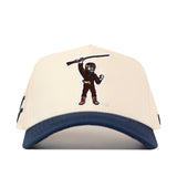Introducing the No Rivals WVU Mountaineers Mascot Patch Hat—a beige and blue baseball cap crafted from performance fabric, featuring an embroidered patch of the Mountaineers mascot holding a rifle above their head. Designed for ultimate comfort, it includes a snap back closure for a perfect fit.