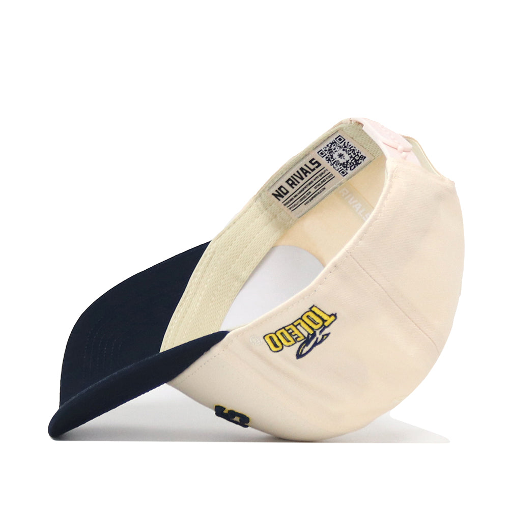 A cream and navy blue snapback baseball cap, the officially licensed “Toledo Rockets | Upside Down Rockets Hat - Classic” by No Rivals, is flipped upside down to display a Toledo logo on the side as well as interior labels featuring a QR code and “NO RIVALS” text.