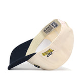 A cream and navy blue snapback baseball cap, the officially licensed “Toledo Rockets | Upside Down Rockets Hat - Classic” by No Rivals, is flipped upside down to display a Toledo logo on the side as well as interior labels featuring a QR code and “NO RIVALS” text.