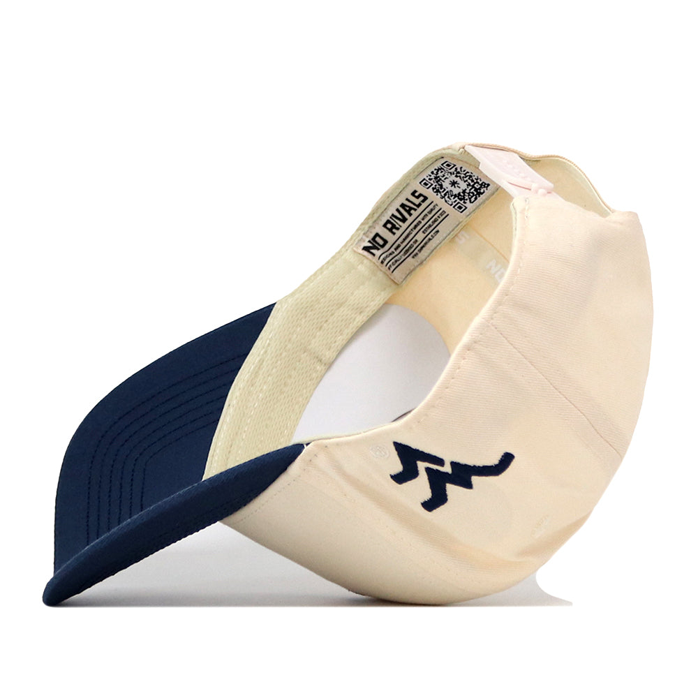 A cream and navy blue WVU Mountaineers Mascot Patch Hat by No Rivals is displayed from the side and inside, featuring a zigzag logo on the front and an interior label that reads NO RIVALS. This officially licensed cap includes a convenient snap back closure for an adjustable fit.