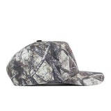 A side view of the No Rivals Bowling Green State Falcons Outland Hat—a flat-brimmed snapback with a camouflage pattern of branches and leaves, featuring an embroidered logo—set against a white background.