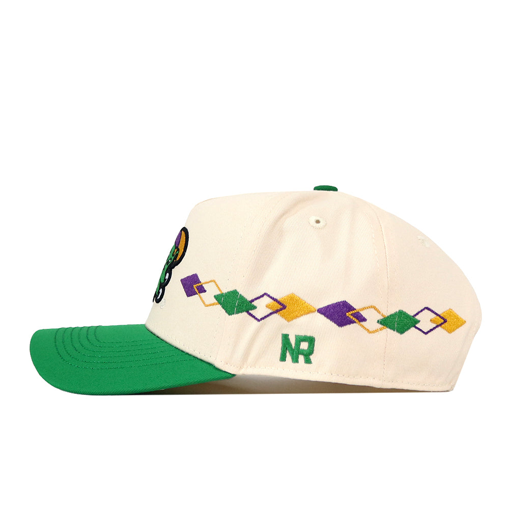 The No Rivals Tulane Mardi Gras Argyle Hat is a cream baseball cap with a green brim, featuring an argyle pattern of interlocking purple, yellow, and green shapes on the side and the letters “NR” embroidered in green. This snapback cap also includes an embroidered logo for a stylish and customizable fit.
