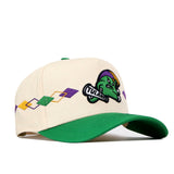 The Tulane Mardi Gras Argyle Hat by No Rivals is a cream baseball cap with a green brim, showcasing an officially licensed cartoon mascot with Tulane text and a diamond pattern in purple, yellow, and green along the side. This stylish snapback also features an embroidered logo for added detail.