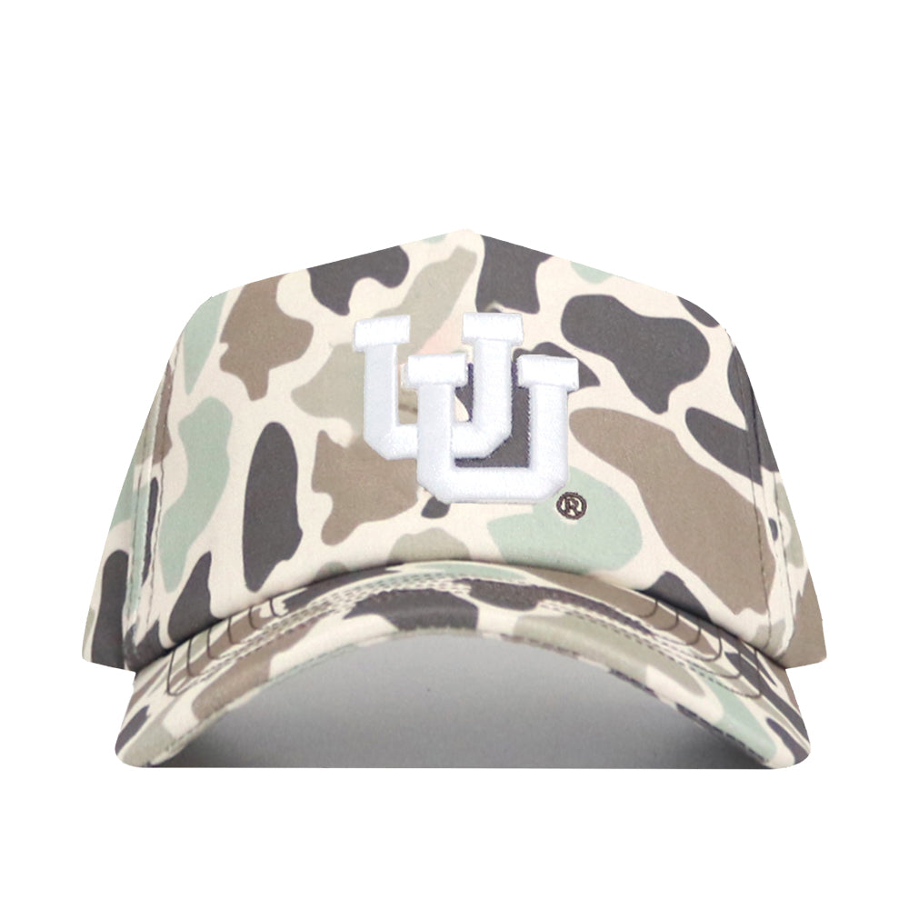 The Utah Huntsman Hat by No Rivals is a 5-panel snap back featuring duck camo in beige, brown, green, and black, with a white embroidered UU logo on the front.