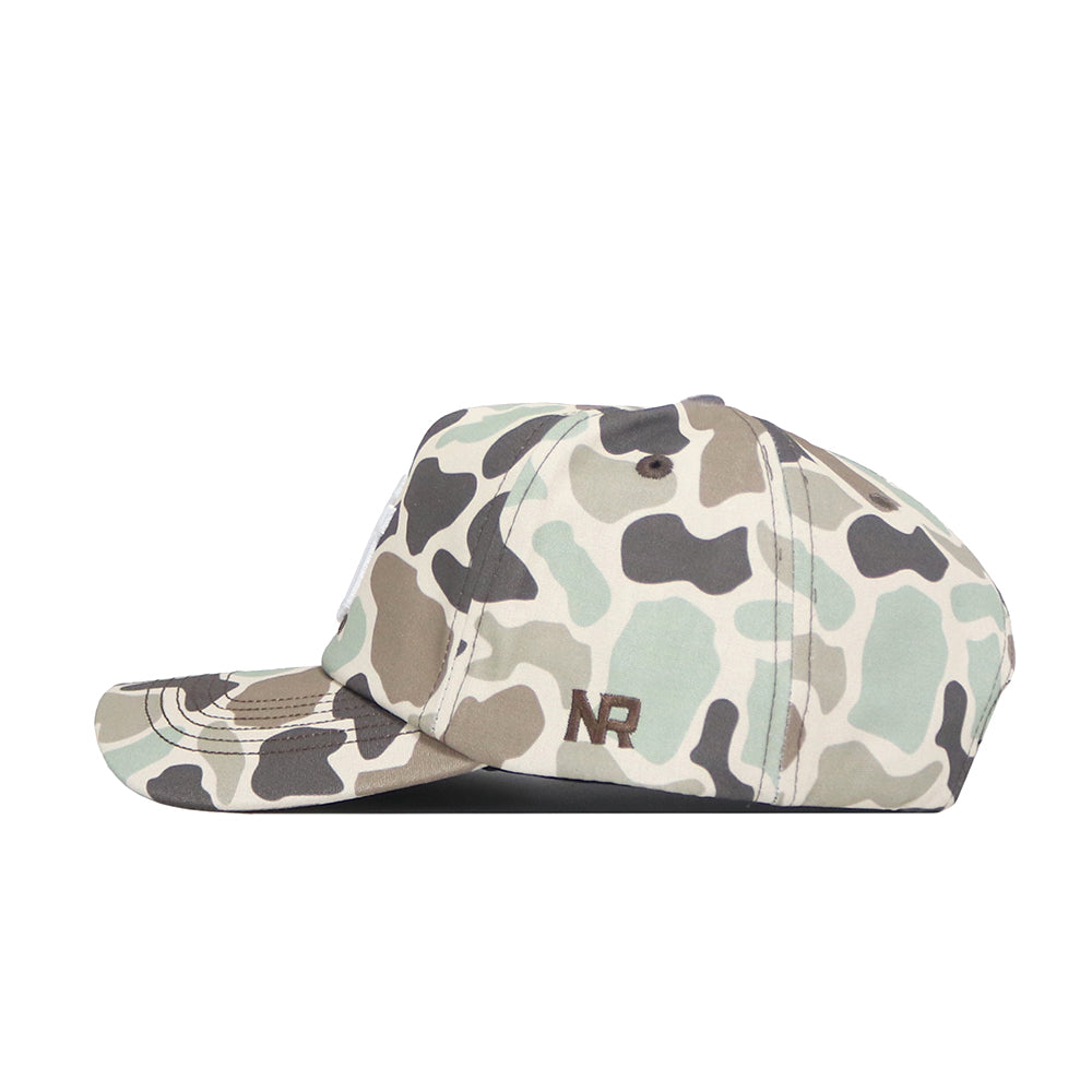 The Utah Huntsman Hat by No Rivals is a 5-panel duck camo cap in earth tones, featuring "NR" embroidered in brown on the side and a classic snapback style, shown from the left on a white background.