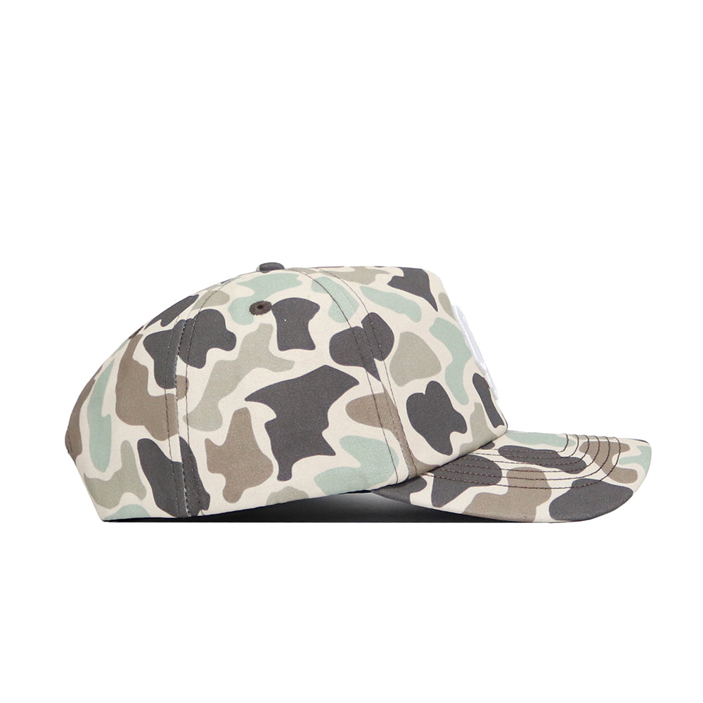 The No Rivals Oklahoma Huntsman Hat is a 5-panel duck camo hat in green, brown, black, and beige camouflage. Shown from the side on a white background, it features a snap back adjustment for comfort.