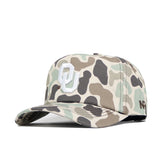 The Oklahoma Huntsman Hat by No Rivals features a white OU logo on duck camo, a small 47 logo on the side, and a 5-panel design blending beige, green, and brown for classic style.