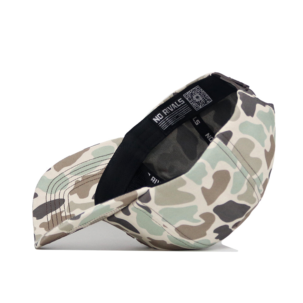 The Texas Tech Huntsman Hat by No Rivals, a 5-panel baseball cap in light green, beige, and brown camo, rests on its side showing an inside No Rivals label, visible QR code, snapback closure, and curved brim.