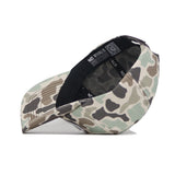 The BYU Huntsman Hat by No Rivals, a 5-panel duck camo cap, is displayed upside down on a white background to show the interior label and stitching.