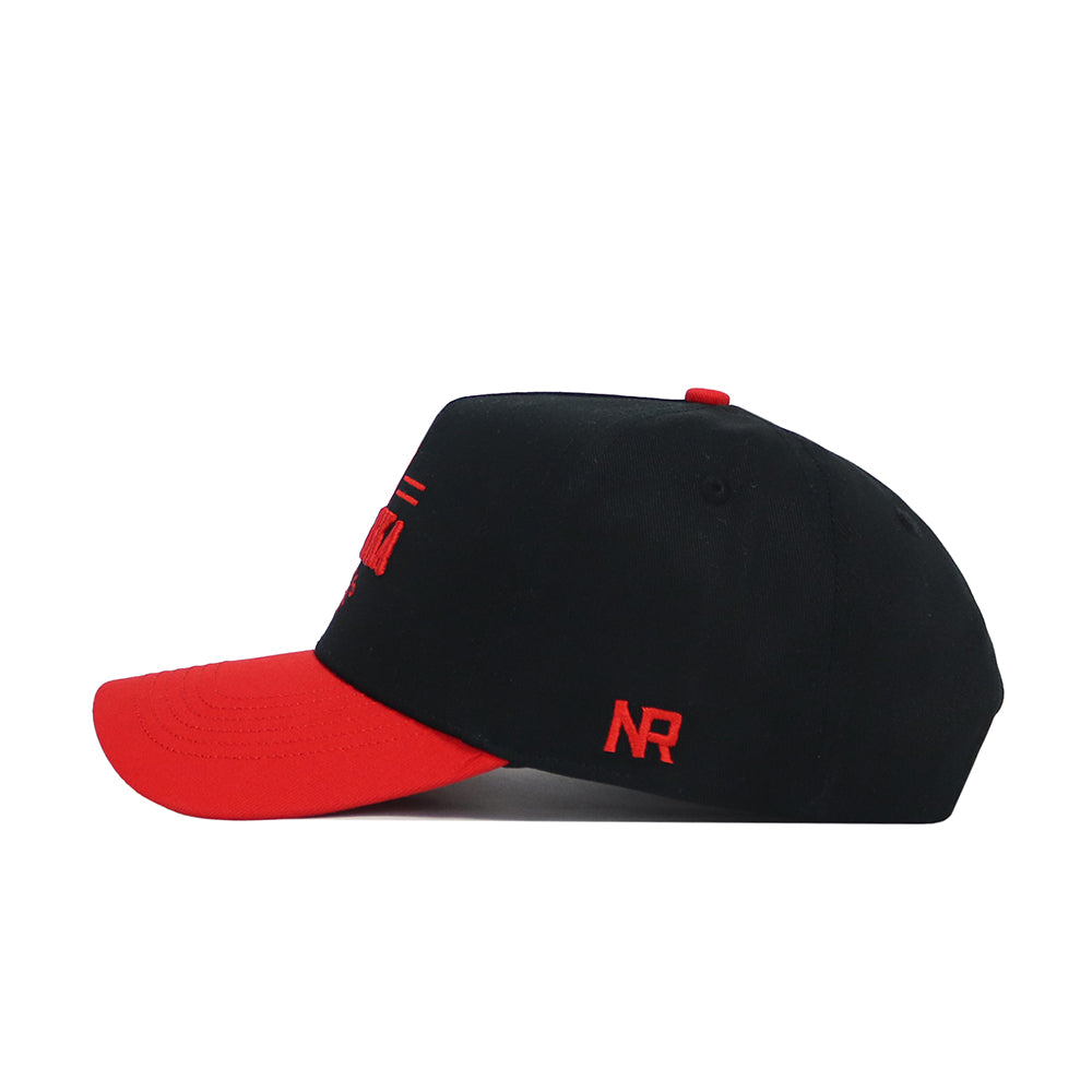 The No Rivals Nebraska Tailgate Hat is a structured black snapback with a red curved brim and red NR embroidery on the side, made from high quality cotton. Shown in a left side profile against a white background.