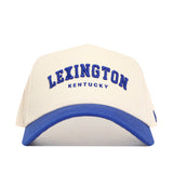 The Lexington Hometown Hat by No Rivals is a white cotton baseball cap with a blue brim, featuring "LEXINGTON KENTUCKY" embroidered in blue on the front and an adjustable snap back for a structured, comfortable fit.