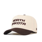 Introducing the North Dakota Espresso Hat by No Rivals—a beige cap featuring "NORTH DAKOTA" boldly embroidered in brown lettering across the front. It showcases a dark brown bill and a practical snapback closure, expertly combining classic style with exceptional quality. Officially licensed and crafted for lasting wear.