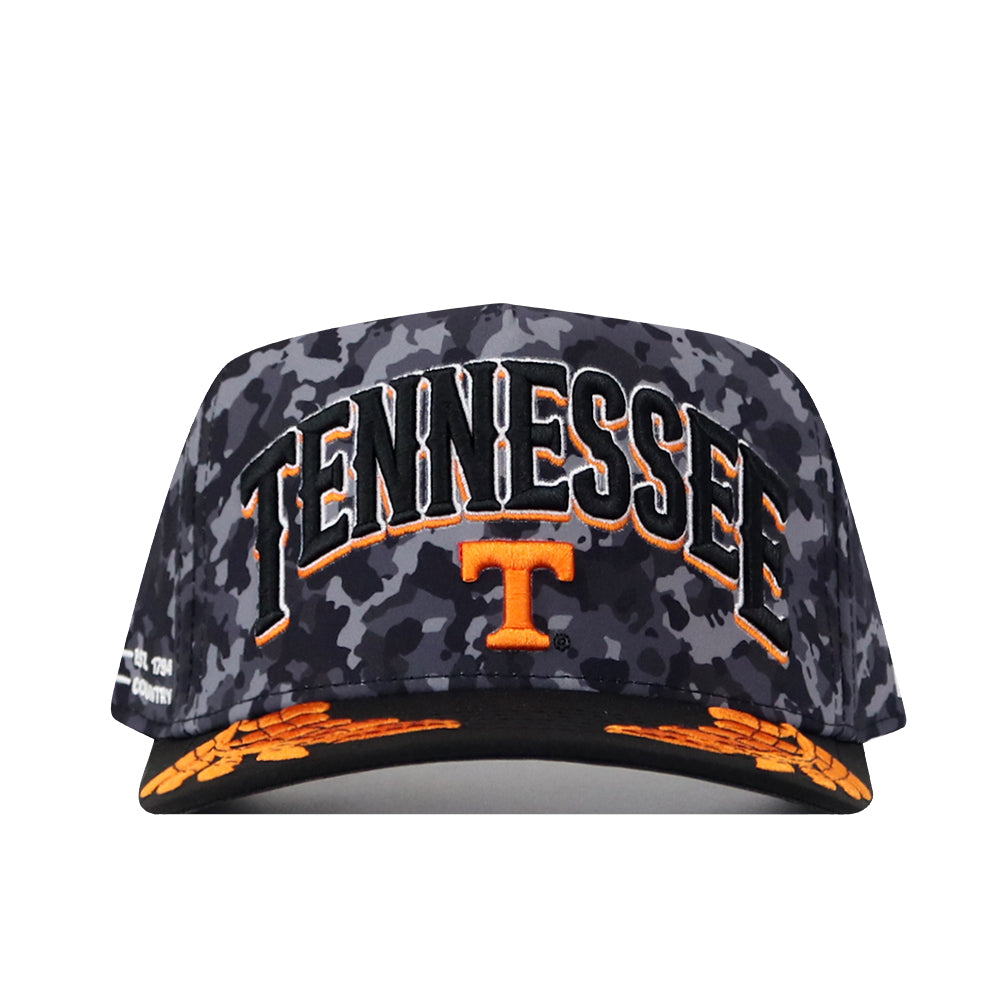 Show your Volunteer pride with the No Rivals Tennessee Volunteers 2026 Military Appreciation Hat. This black and gray camo snapback cap features “TENNESSEE” and a large orange T boldly embroidered on the front, accented by striking orange designs on the brim. The officially licensed hat delivers standout style with its prominent logo—perfect for any fan.