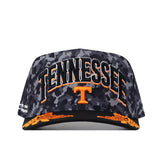 Show your Volunteer pride with the No Rivals Tennessee Volunteers 2026 Military Appreciation Hat. This black and gray camo snapback cap features “TENNESSEE” and a large orange T boldly embroidered on the front, accented by striking orange designs on the brim. The officially licensed hat delivers standout style with its prominent logo—perfect for any fan.