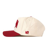 The Indiana Hoosiers Stadium Hat by No Rivals is a cream-colored snapback baseball cap with a red brim, showcasing bold red embroidered logos on the front and side. It is displayed from a side angle on a white background.
