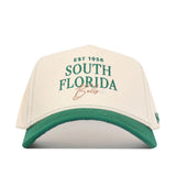 The No Rivals USF Vintage Hat is a white snapback with a green brim, made from premium cotton. Features "EST 1956 SOUTH FLORIDA Bulls" embroidered in green and tan. Officially licensed—perfect for true fans.