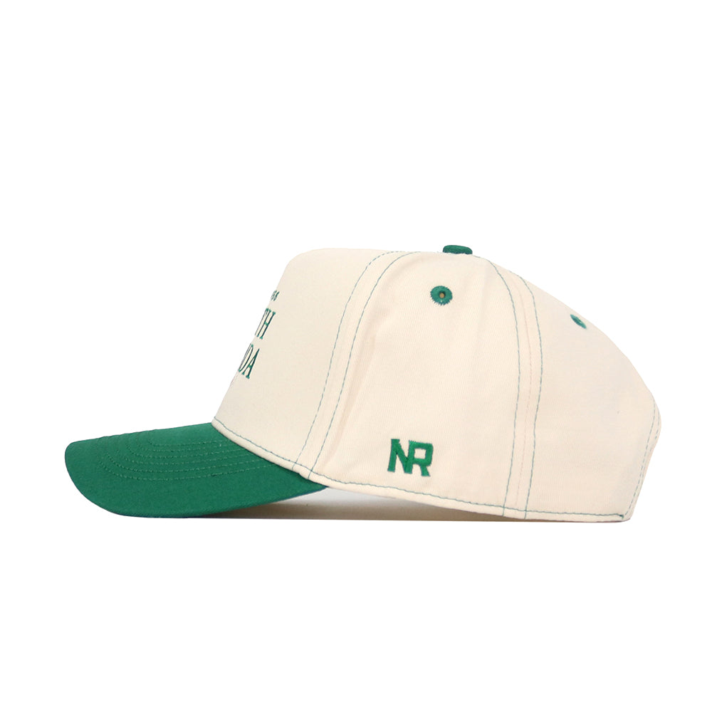 The No Rivals USF Vintage Hat is a cream snapback with a green brim and stitching. "NR" is embroidered in green on the left side near the brim. Crafted from high-quality cotton for lasting comfort and style. Side view shown.