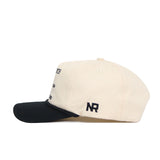 The No Rivals Wake Forest "The Couch" Walk-Off Hat is a beige cotton cap with a black brim, featuring black embroidered NR above the brim. This adjustable hat ensures a comfortable fit and is shown from the side.