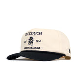 The No Rivals Wake Forest "The Couch" Walk-Off Hat is a cream cotton cap with a black brim, embroidered with "The Couch," "EST 1834," "Demon Deacons," and the mascot logo on front, plus a small black N on the side. Adjustable fit.